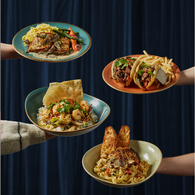 Four plates of restaurant food including pasta, steak sandwich, shrimp bowl and chicken pasta held against a blue backdrop