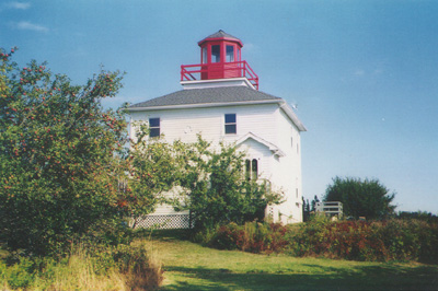 Restored white wooden Burntcoat Head lighthouse with a red cupola on a grassy headland
