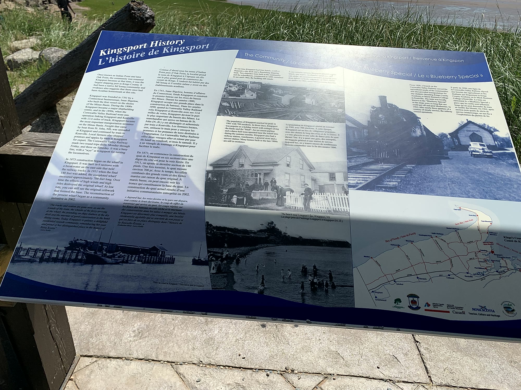Kingsport History interpretive sign near the beach, with bilingual English and French text about the village's shipping and railway past