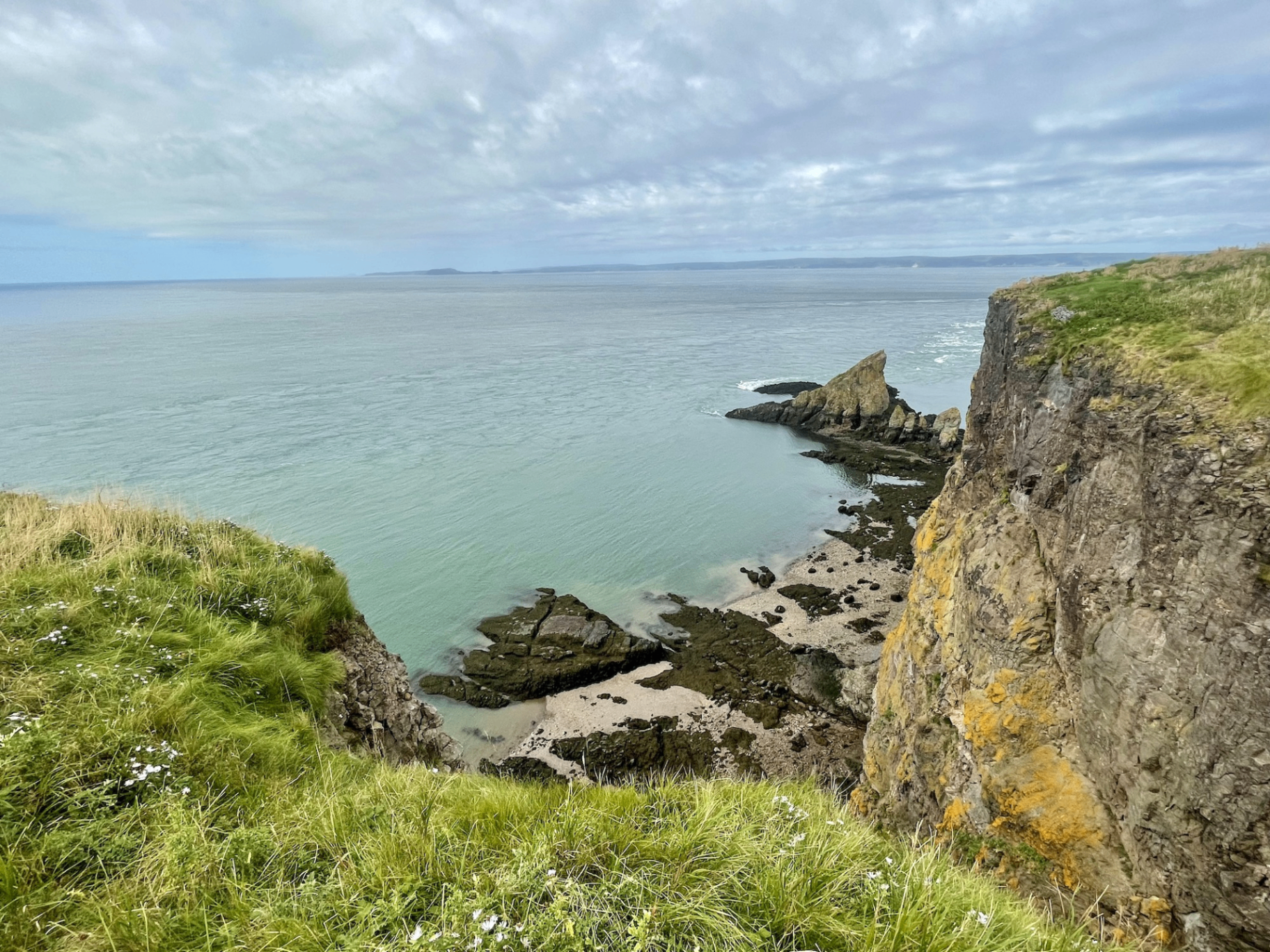 Cliff-top view of the Minas Basin from Cape Split with rocky outcrops and green grass